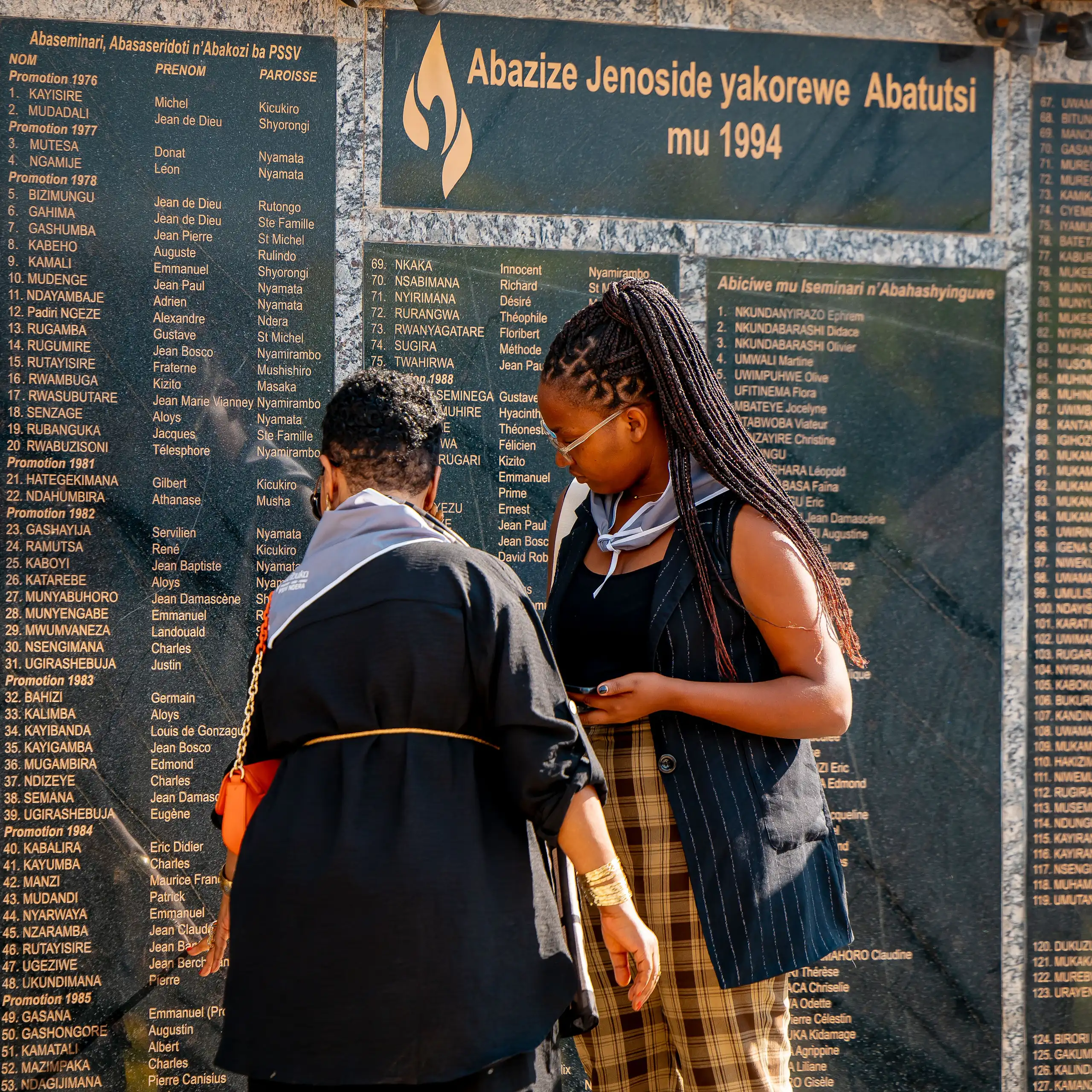 Deux femmes devant la stèle portant les noms des victimes du génocide.