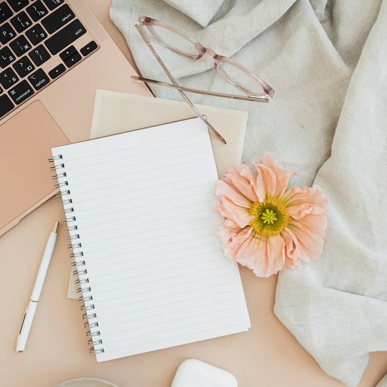 flatlay of notebook, flower, laptop