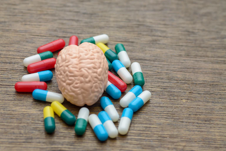 A human brain model surrounded by colourful pills
