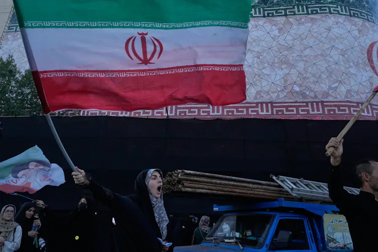A woman waves a flag in a city square.