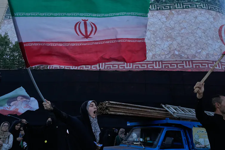 A woman waves a flag in a city square.