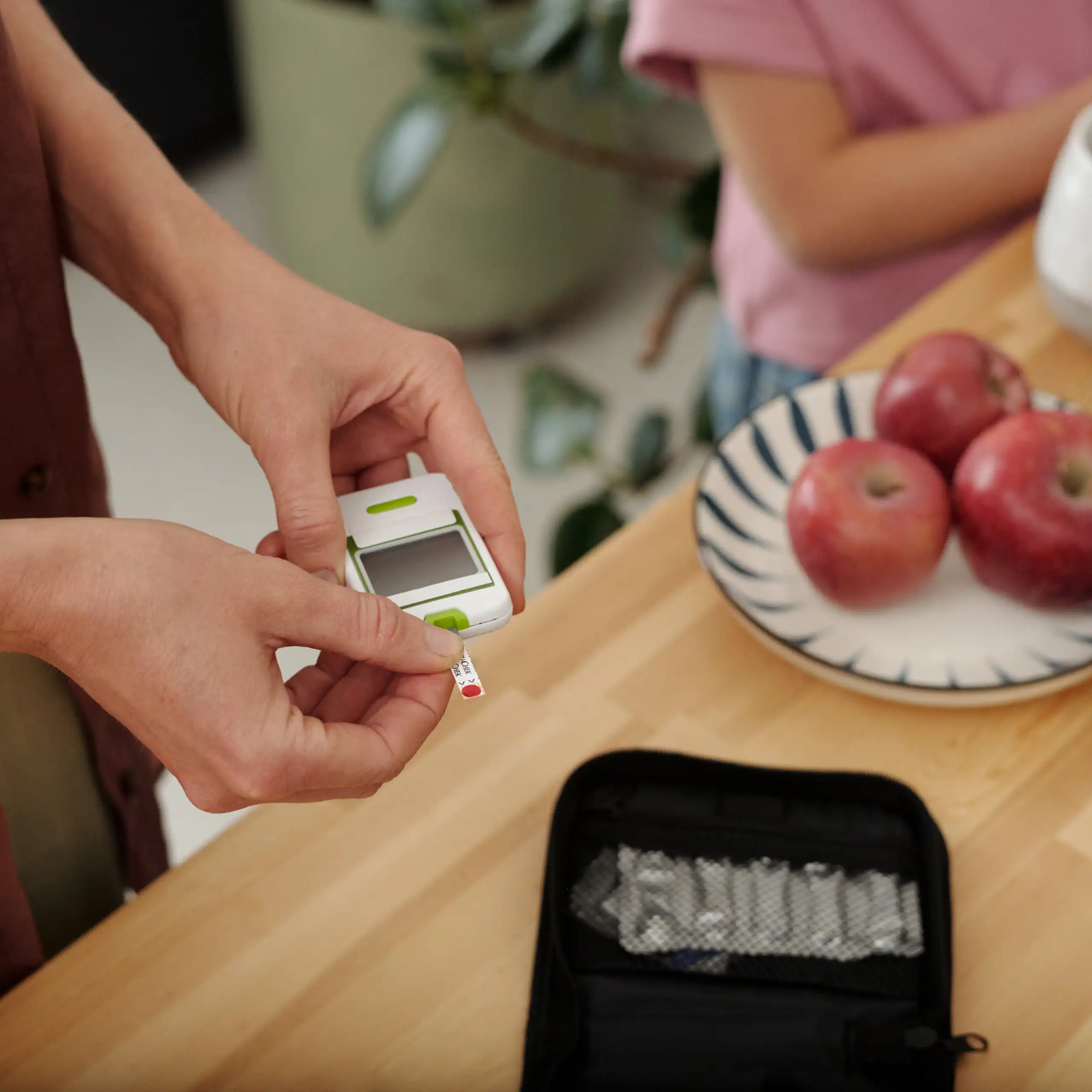 A woman is holding a glucose meter