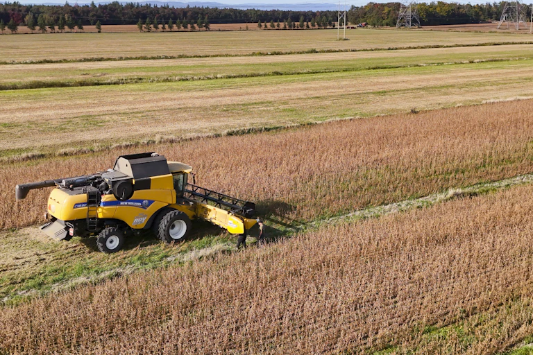 A farmer harvests a soy crop in a harvester