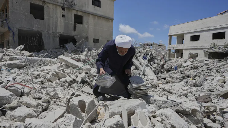 La inteligencia artificial plantea profundas cuestiones morales que toda la humanidad puede responder 2 Un hombre se agacha entre las ruinas del bombardeo con una pila de libros.