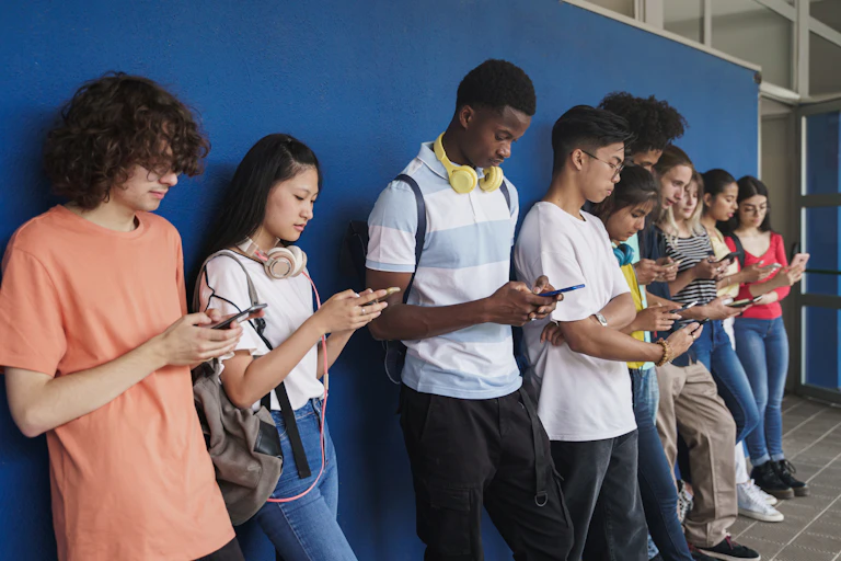 Teenagers leaning against wall looking at phones
