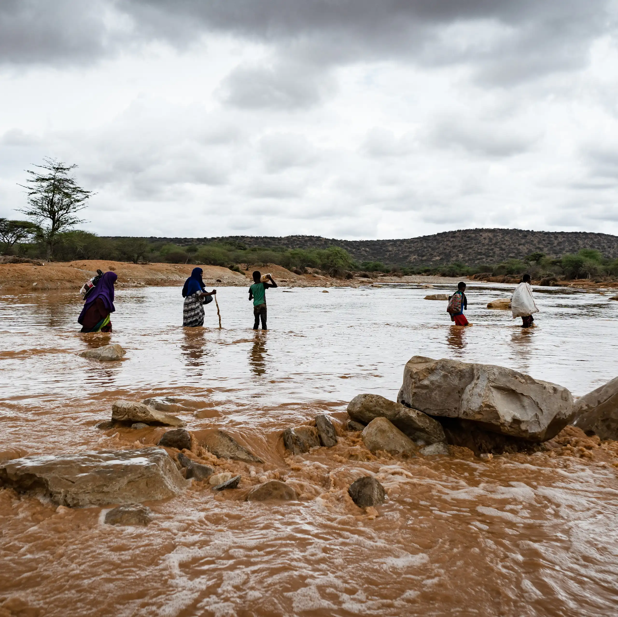 Family in dangerous river crossing during heavy flooding with dramatic sky