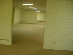 Fotografía de una serie de espacios de oficina vacíos, con luz intermitente, moqueta y papel en las paredes.