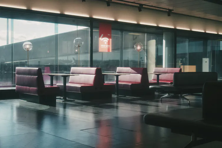 Unas mesas de diner americano ante unas ventanas, en un espacio vacío sin gente.