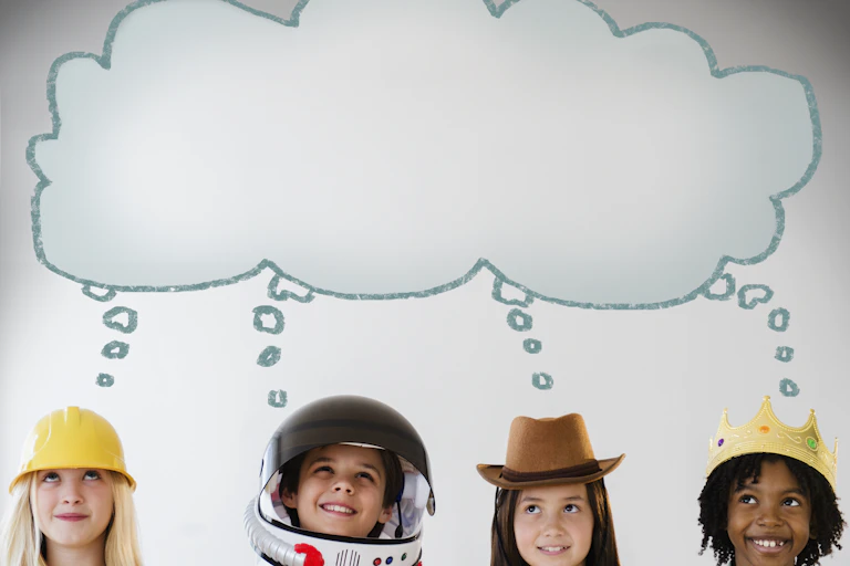 Four children wearing different hats, from a yellow construction hat to an astronaut helmet, stand in a row with a cartoon thought bubble above them all.
