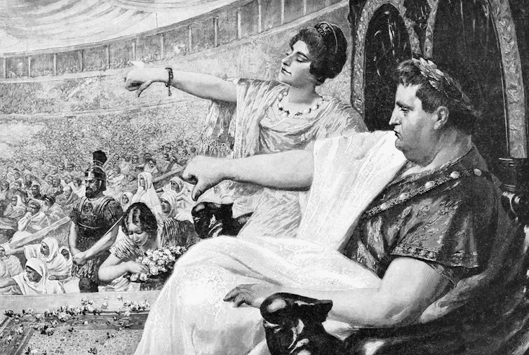A man in Roman dress sitting in a crowd, gesturing thumbs down.