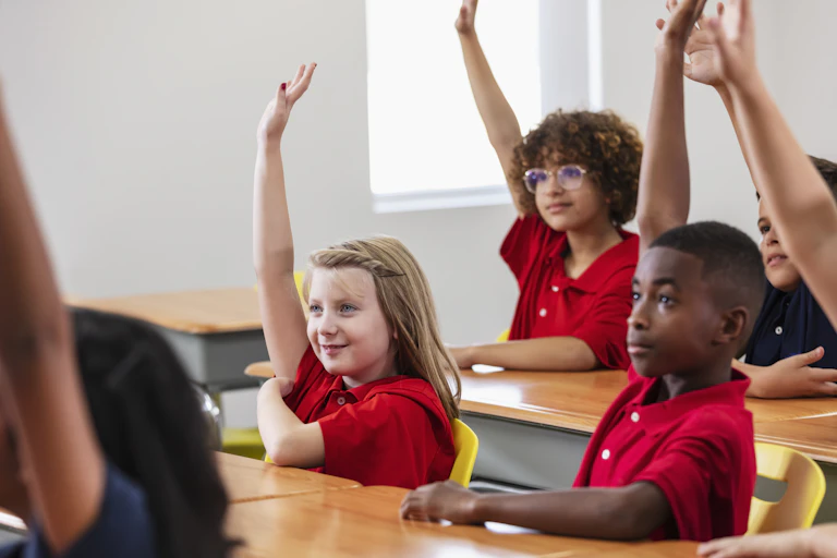 kids in classroom raising their hands