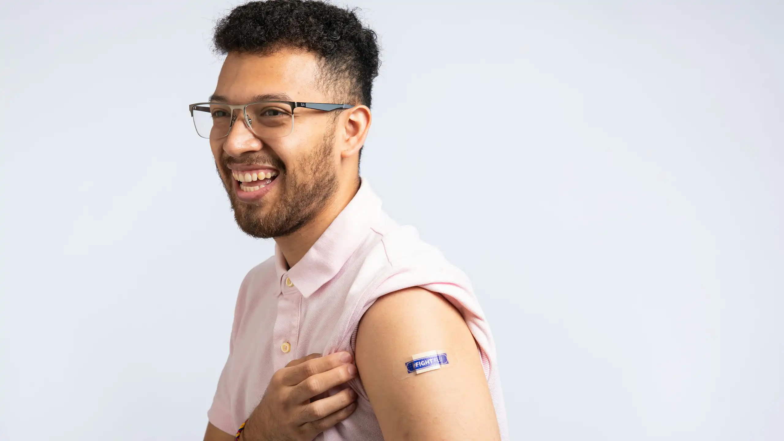 A smiling man with a bandage on his upper arm that reads 'Fight flu'