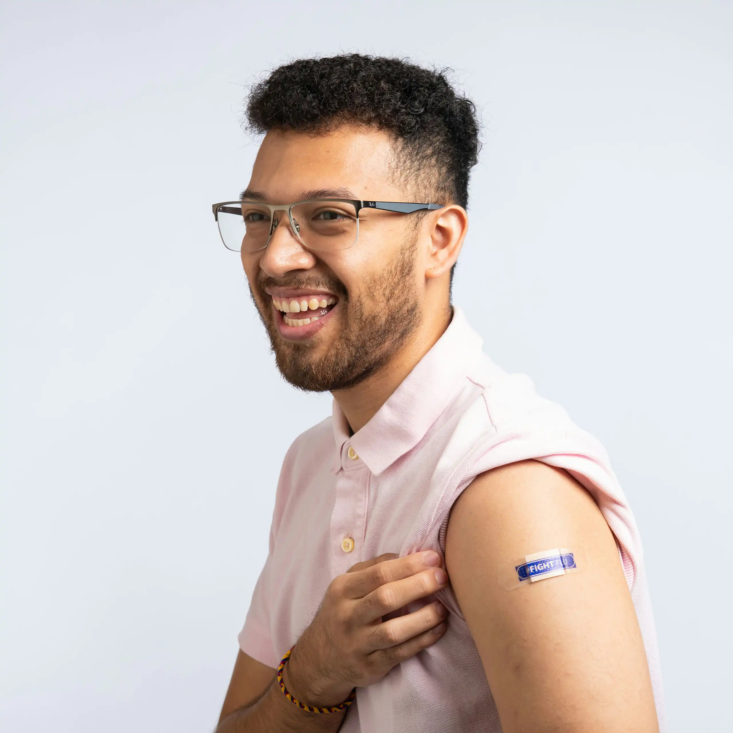 A smiling man with a bandage on his upper arm that reads 'Fight flu'