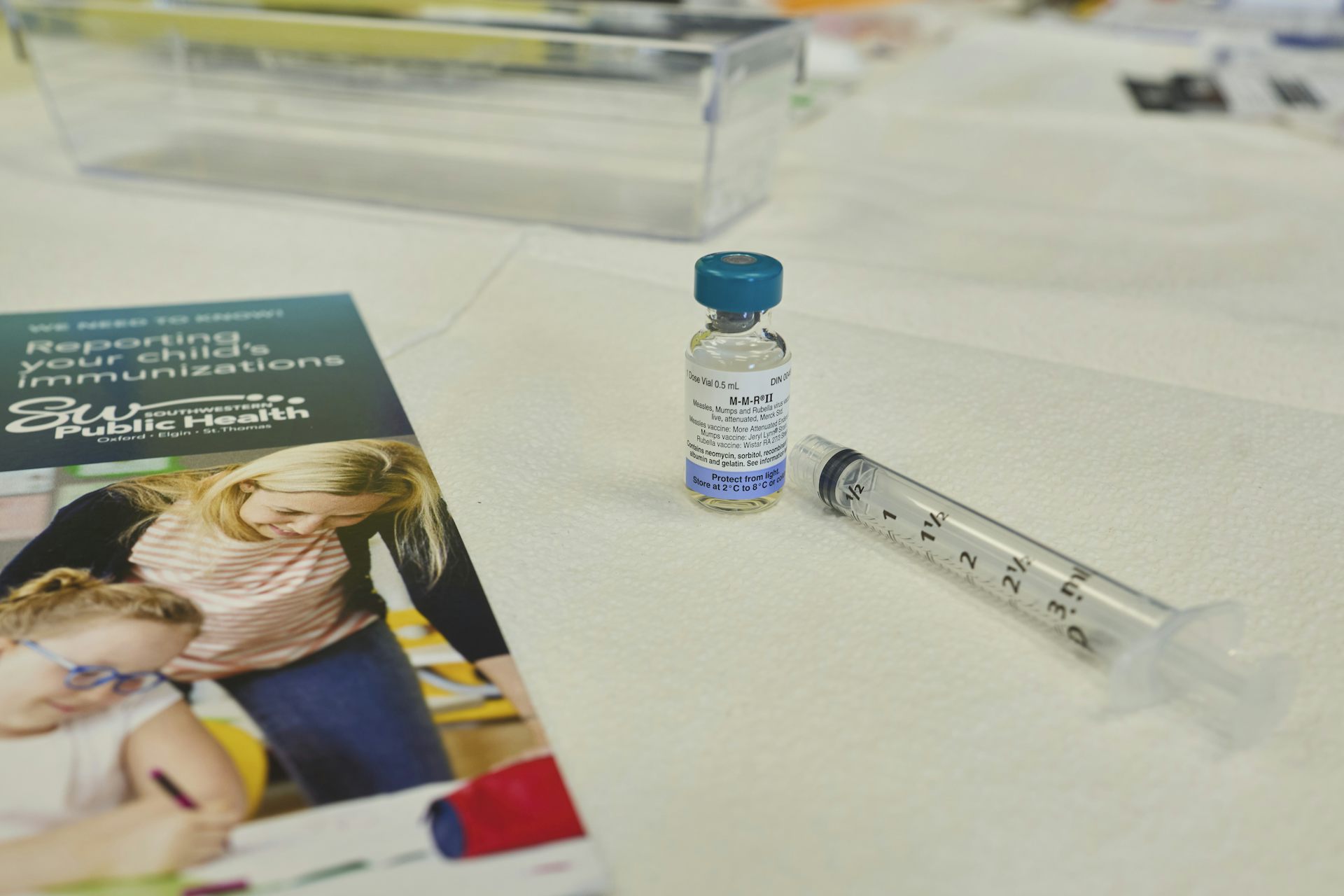 Vial de vacuna, jeringa y folleto sobre mostrador blanco