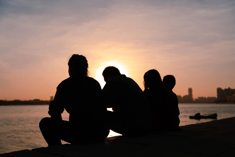 A family is cast in silhouette against a sunset background.