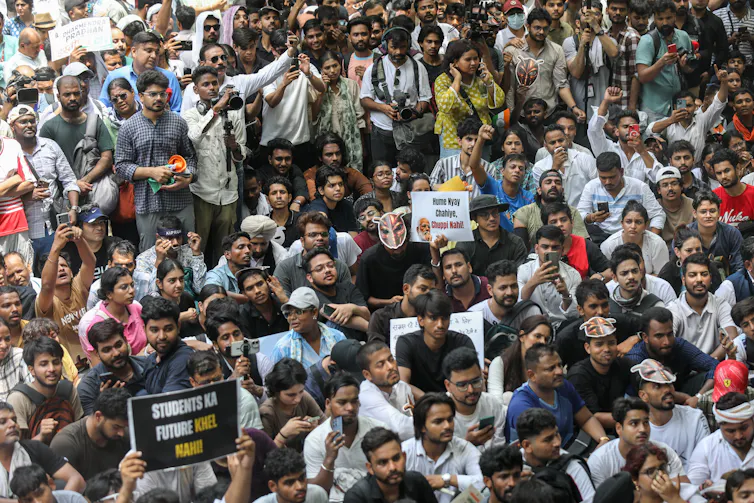 A large crowd of protesters gather tightly in the streets, holding signs