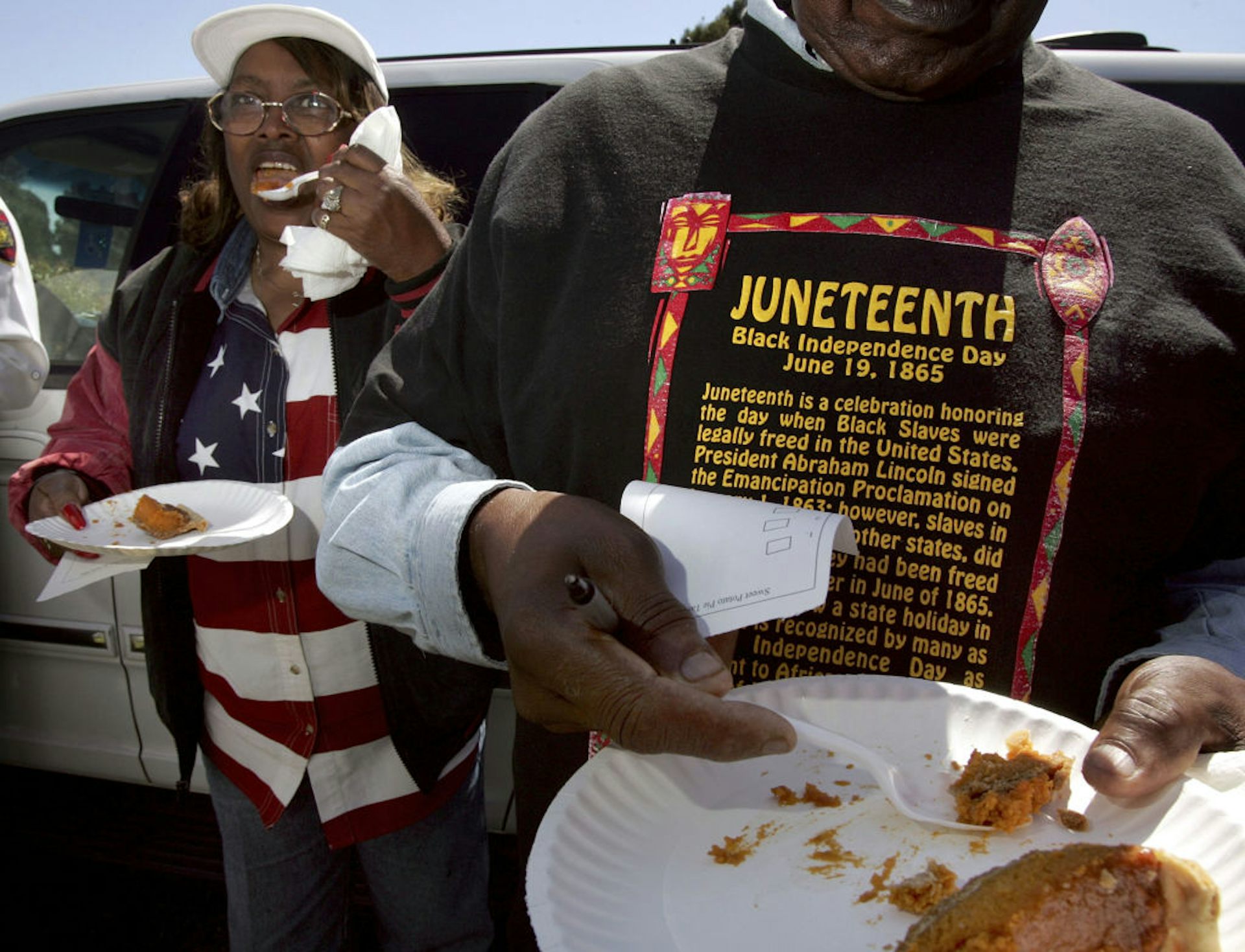 A Black woman and a Black man eat pie from paper plates.