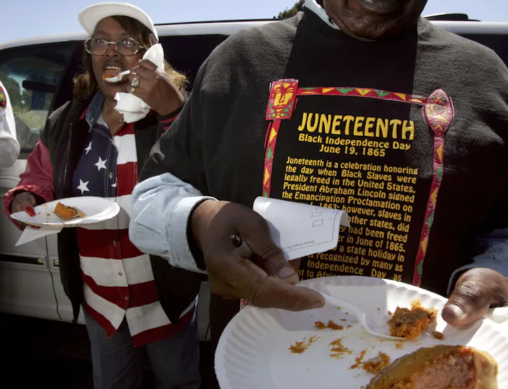 A Black woman and a Black man eat pie from paper plates.