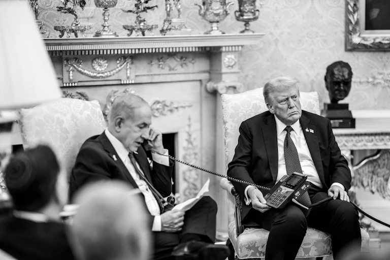 Israeli PM Benjamin Netanyahu speaks into a telephone held by an unsmiling US president Donald Trump.
