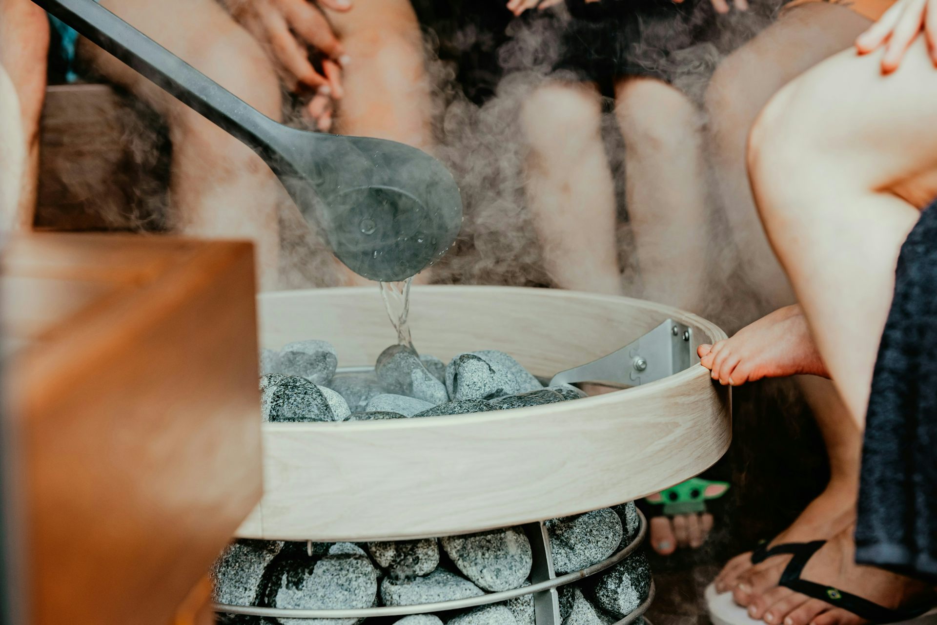 Poêle de sauna avec des pierres chaudes, de la vapeur et des gens assis autour