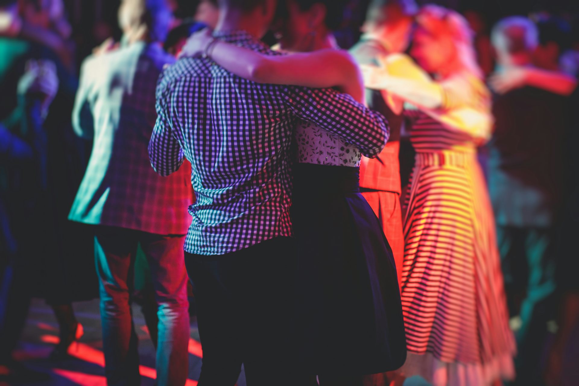 Des couples dansant dans lé pénombre sur une piste de danse. 