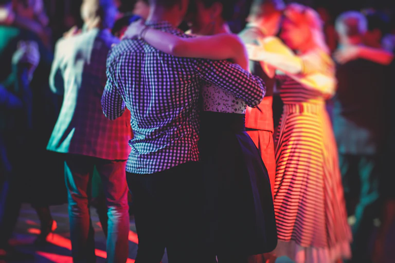 Des couples dansant dans lé pénombre sur une piste de danse.