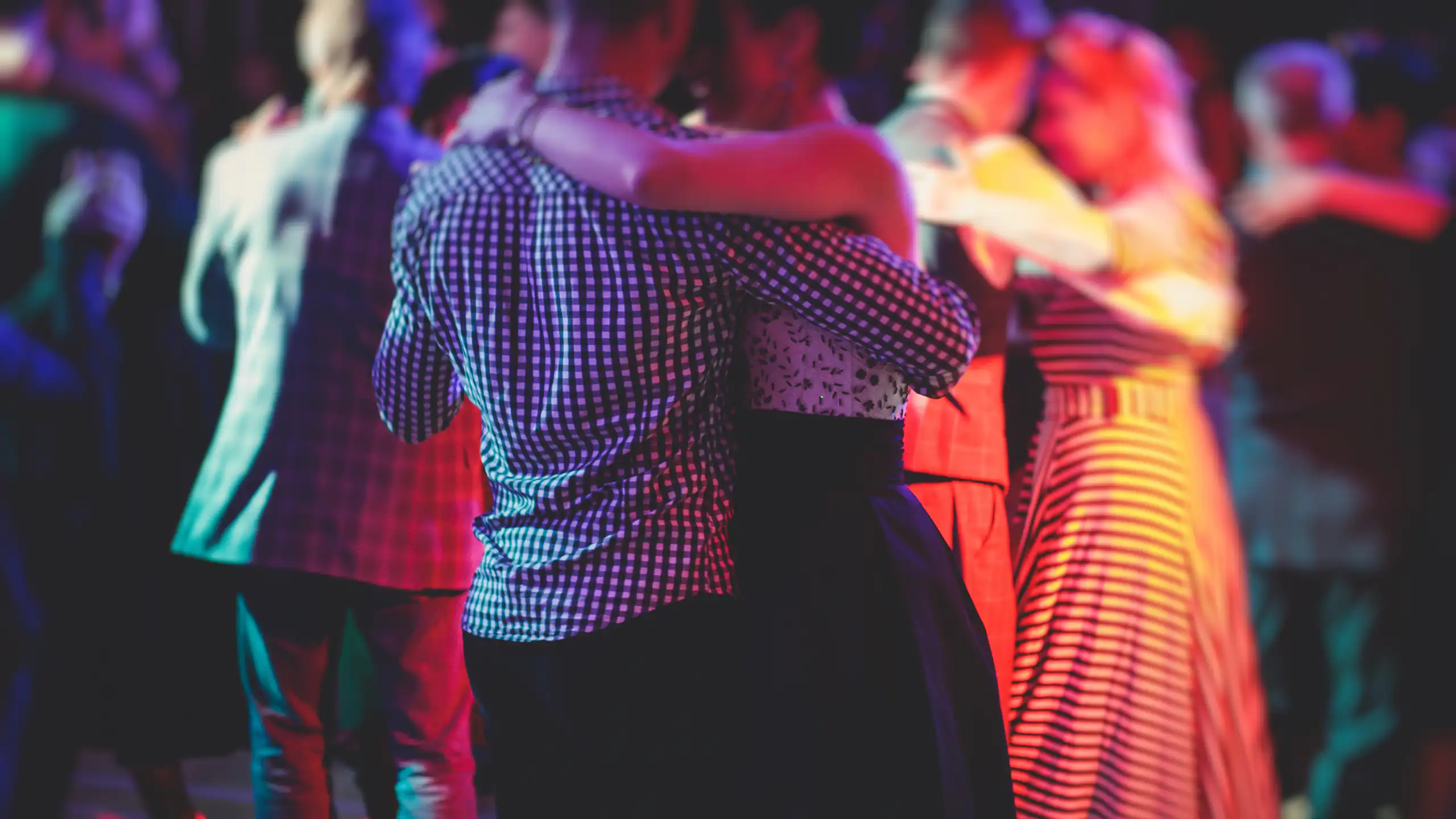 Des couples dansant dans lé pénombre sur une piste de danse.