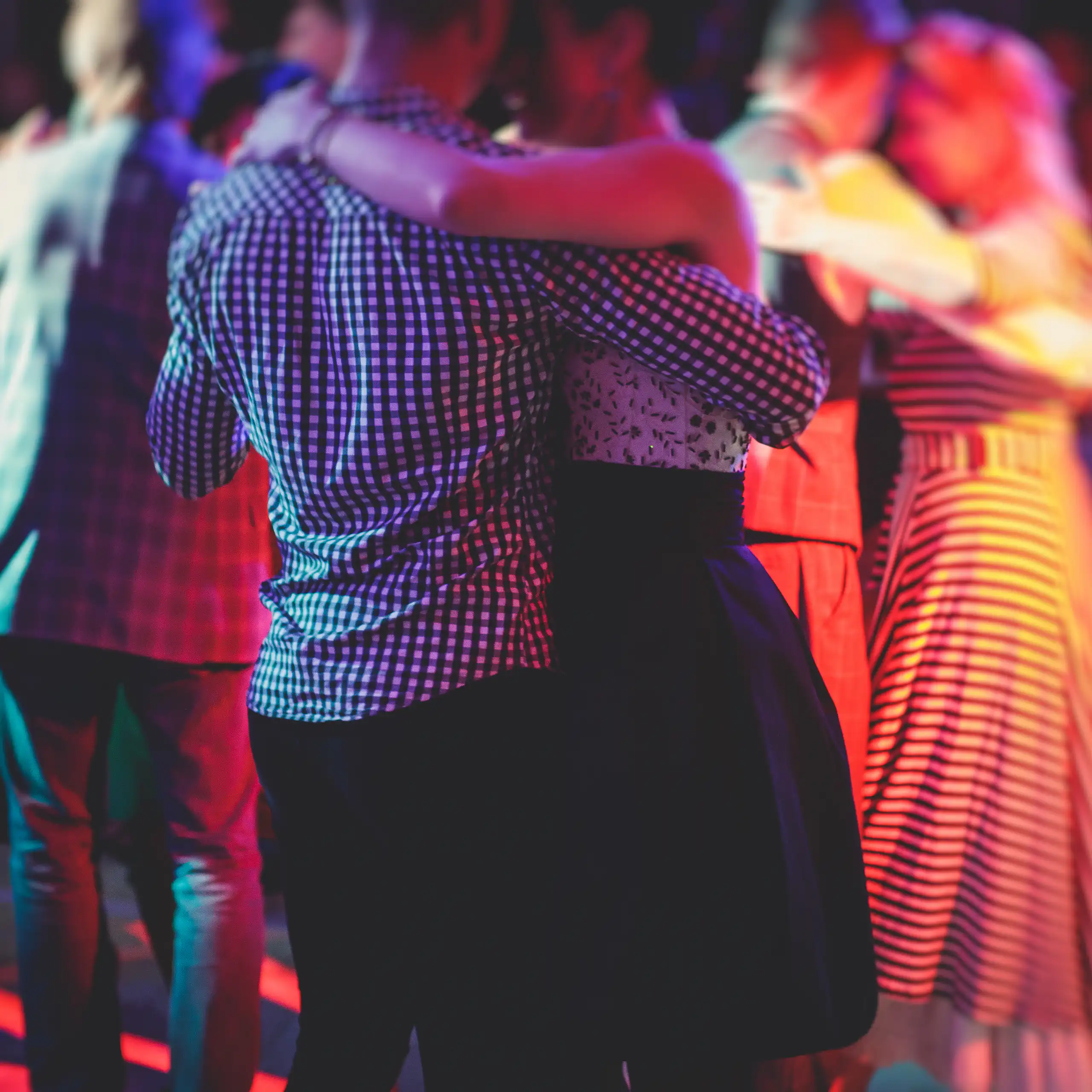 Des couples dansant dans lé pénombre sur une piste de danse.