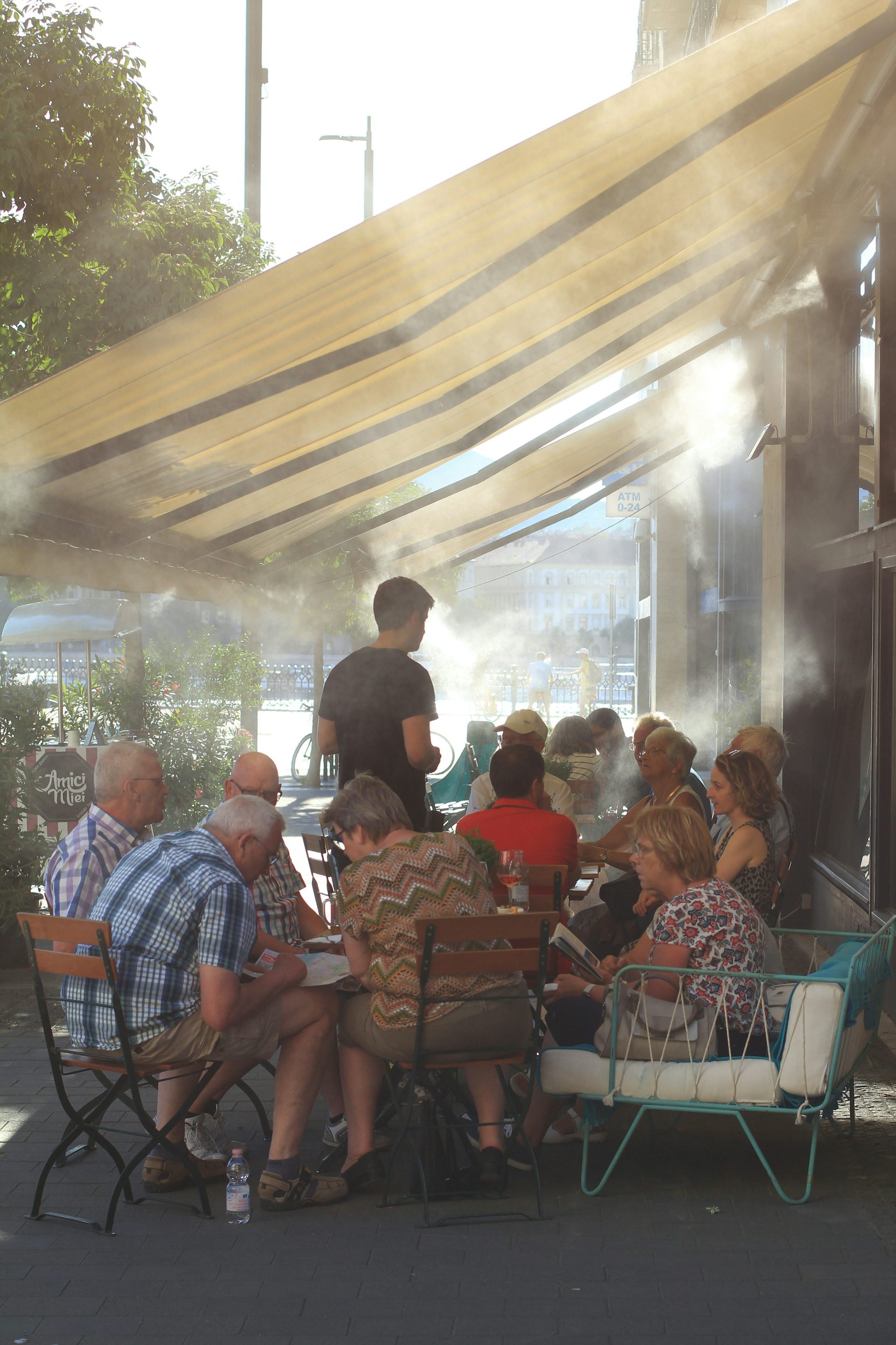 Un groupe de personnes ainées assis autour d’une table à l’extérieur durant une canicule