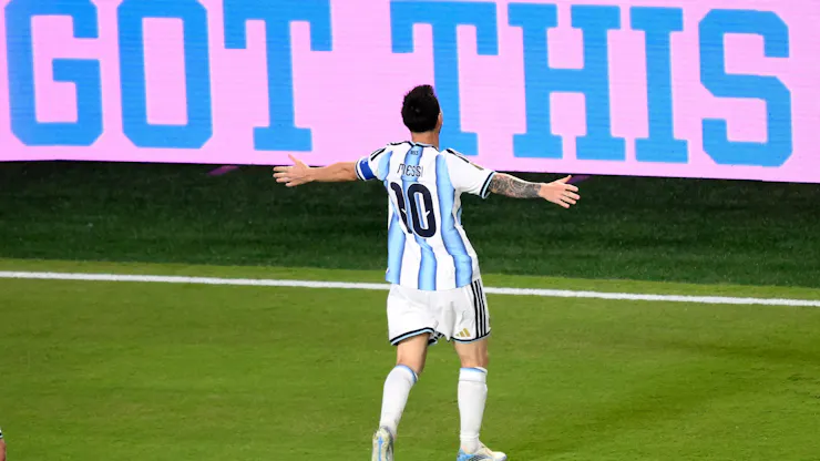 A man in a blue and white jersey has his arms outstretched.