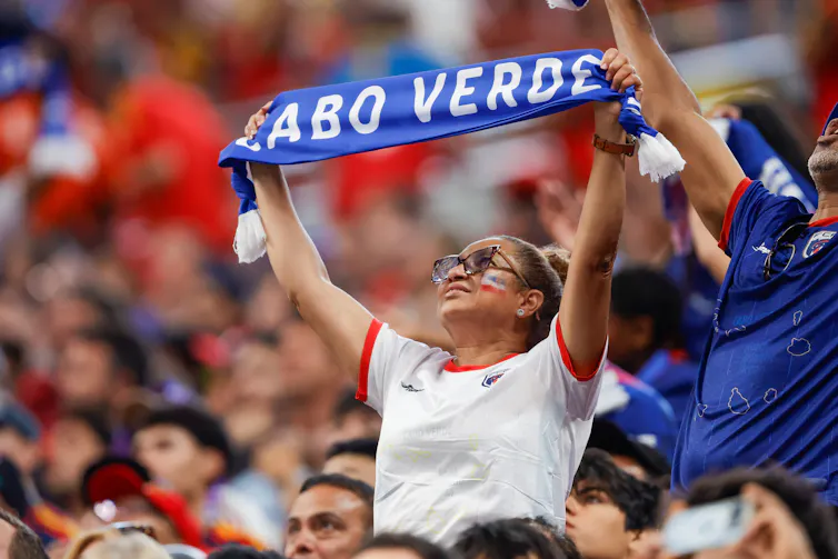 Una mujer sostiene una bufanda con una inscripción.