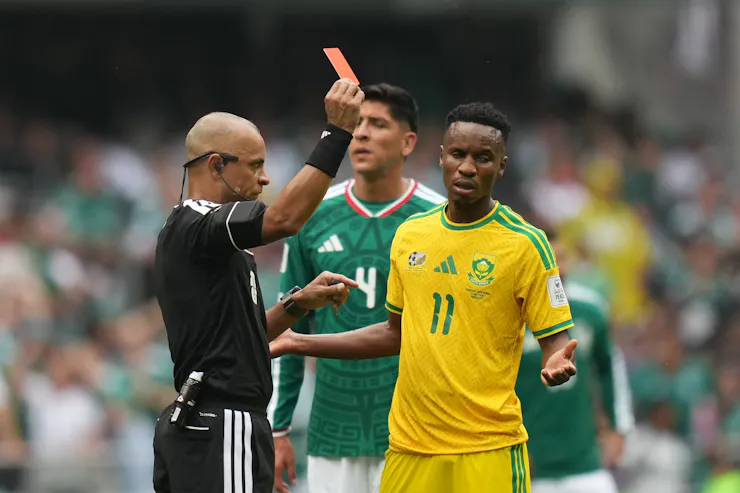 A man dressed in black holds aloft a red card.