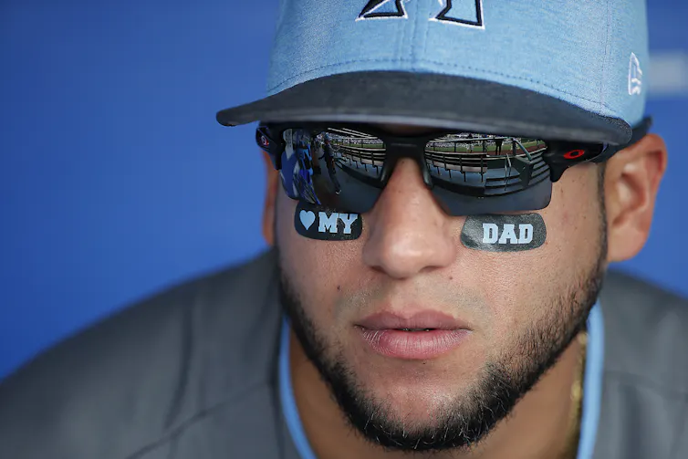 Baseball players wearing hats and sunglasses also sport eye-black stickers that say: