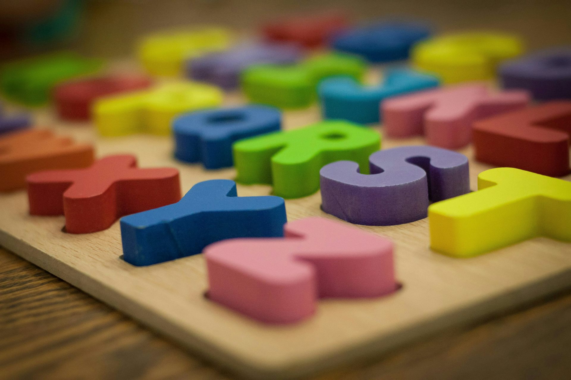 Wooden manipulable letters of the alphabet seen in a box.