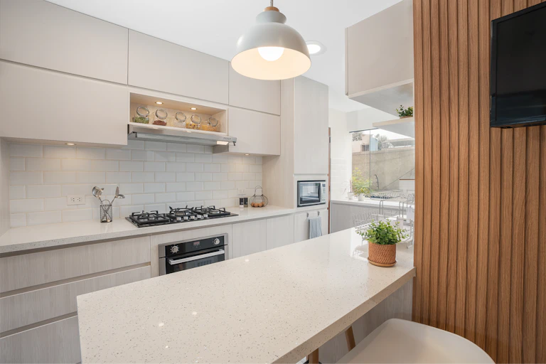 A newly remodeled kitchen with off-white countertops made of engineered stone