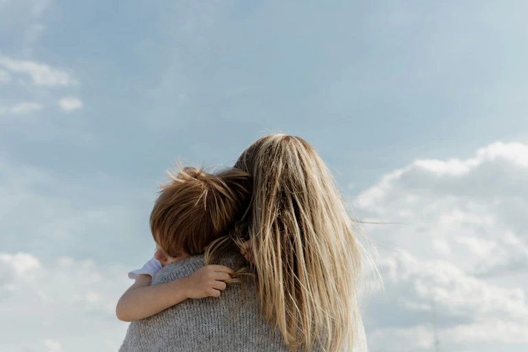 The back of a woman with long blonde hair holding a young boy