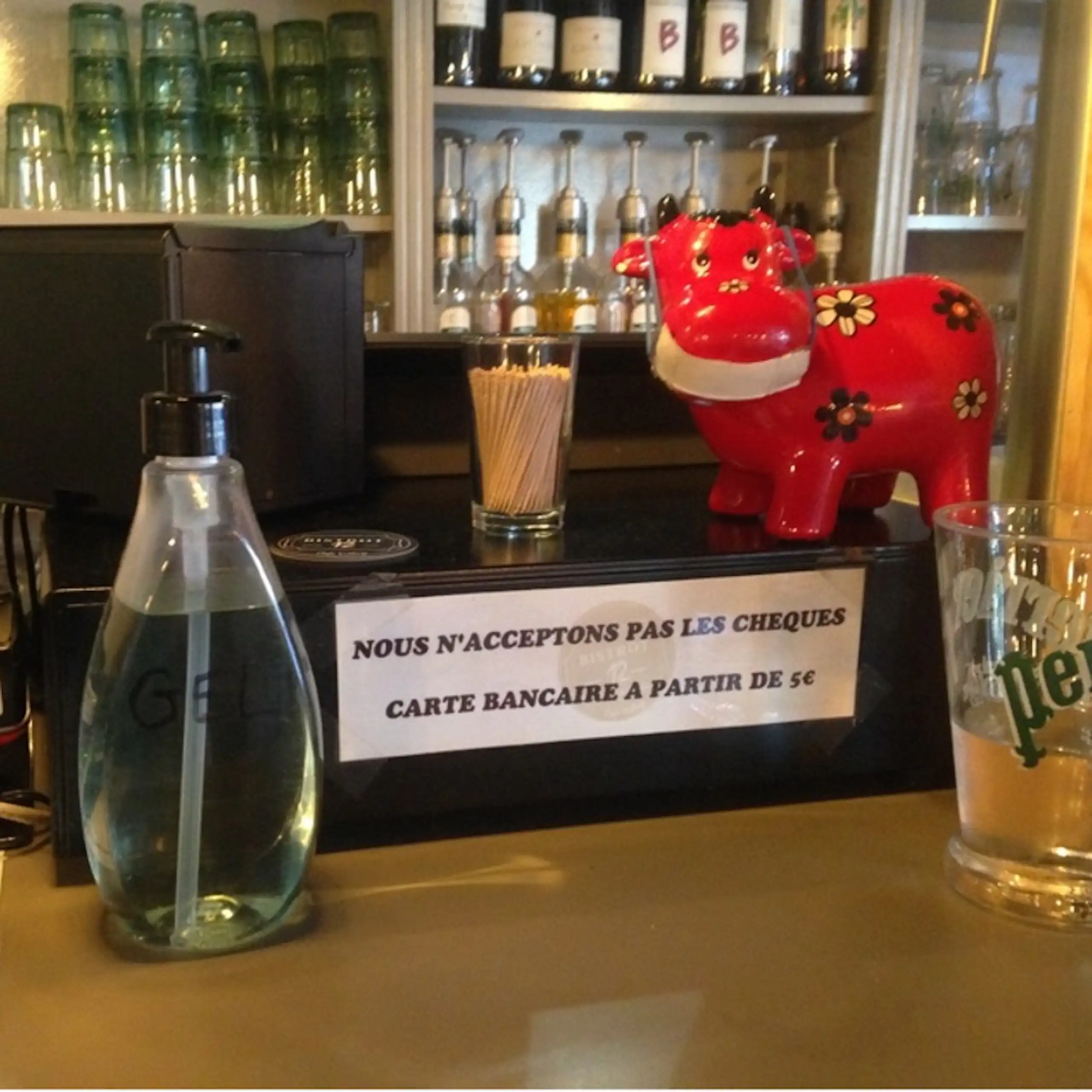 Caisse dans un bar avec écrit « Nous n'acceptons pas les chèques. Carte bancaire à partir de 1 euro ».