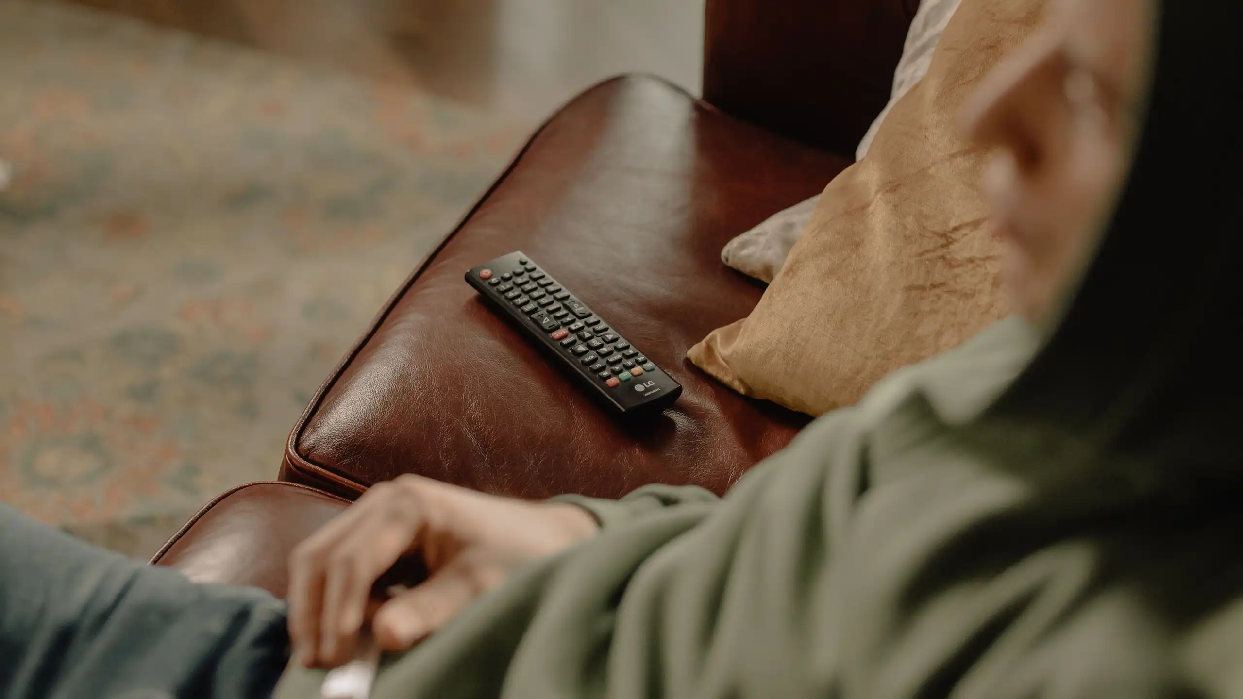 A boy sitting on the couch with the TV remote next to him