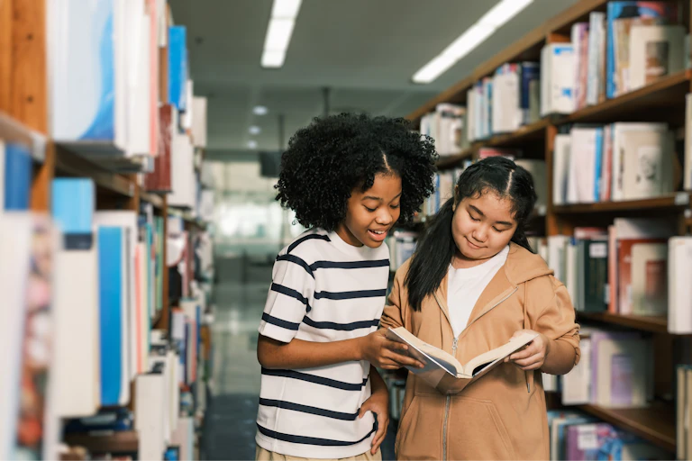 Two girls looking at book in library