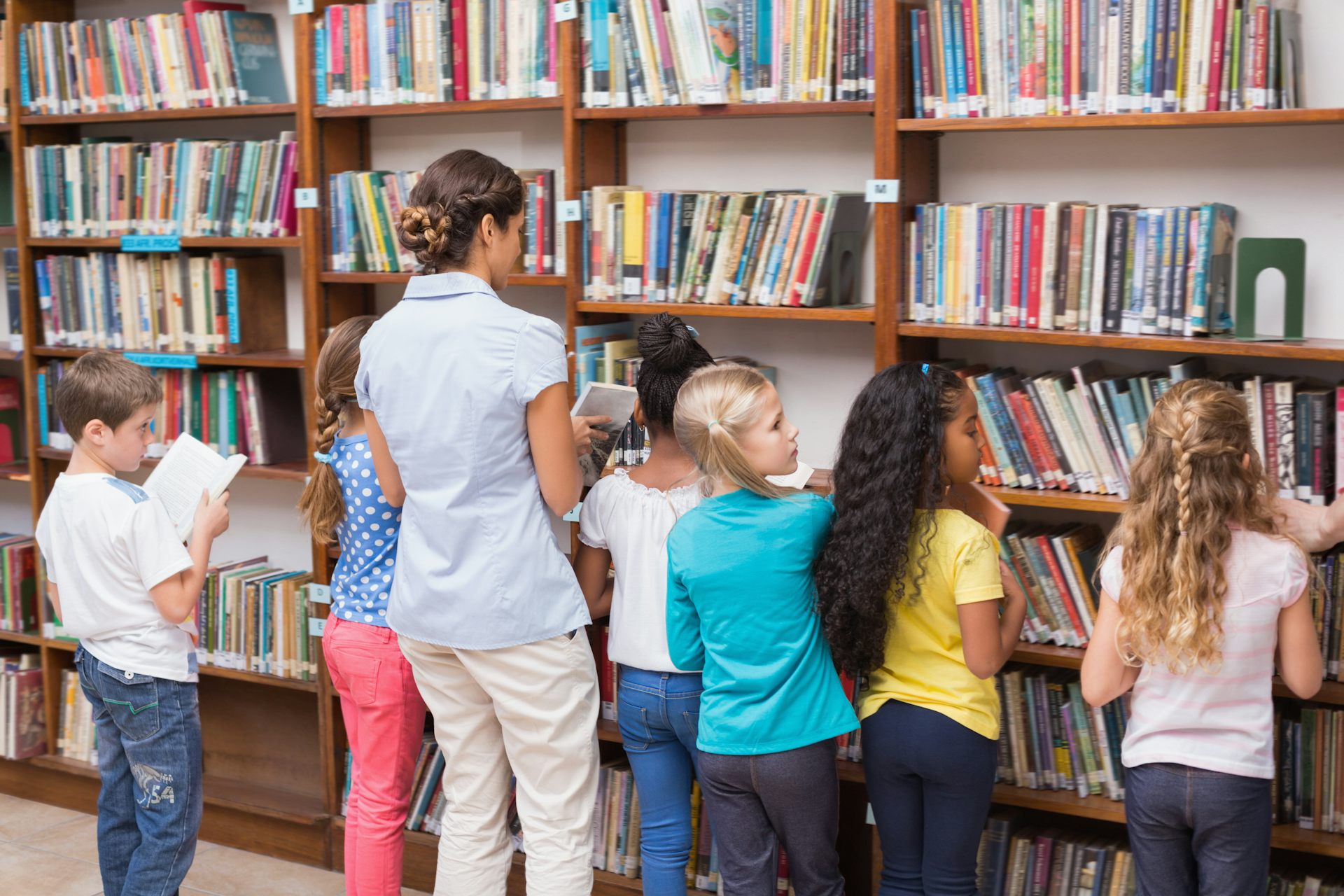 Children and teacher in school library