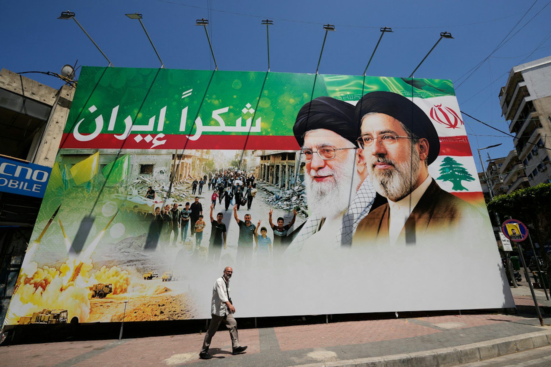 A man walks by a giant billboard.
