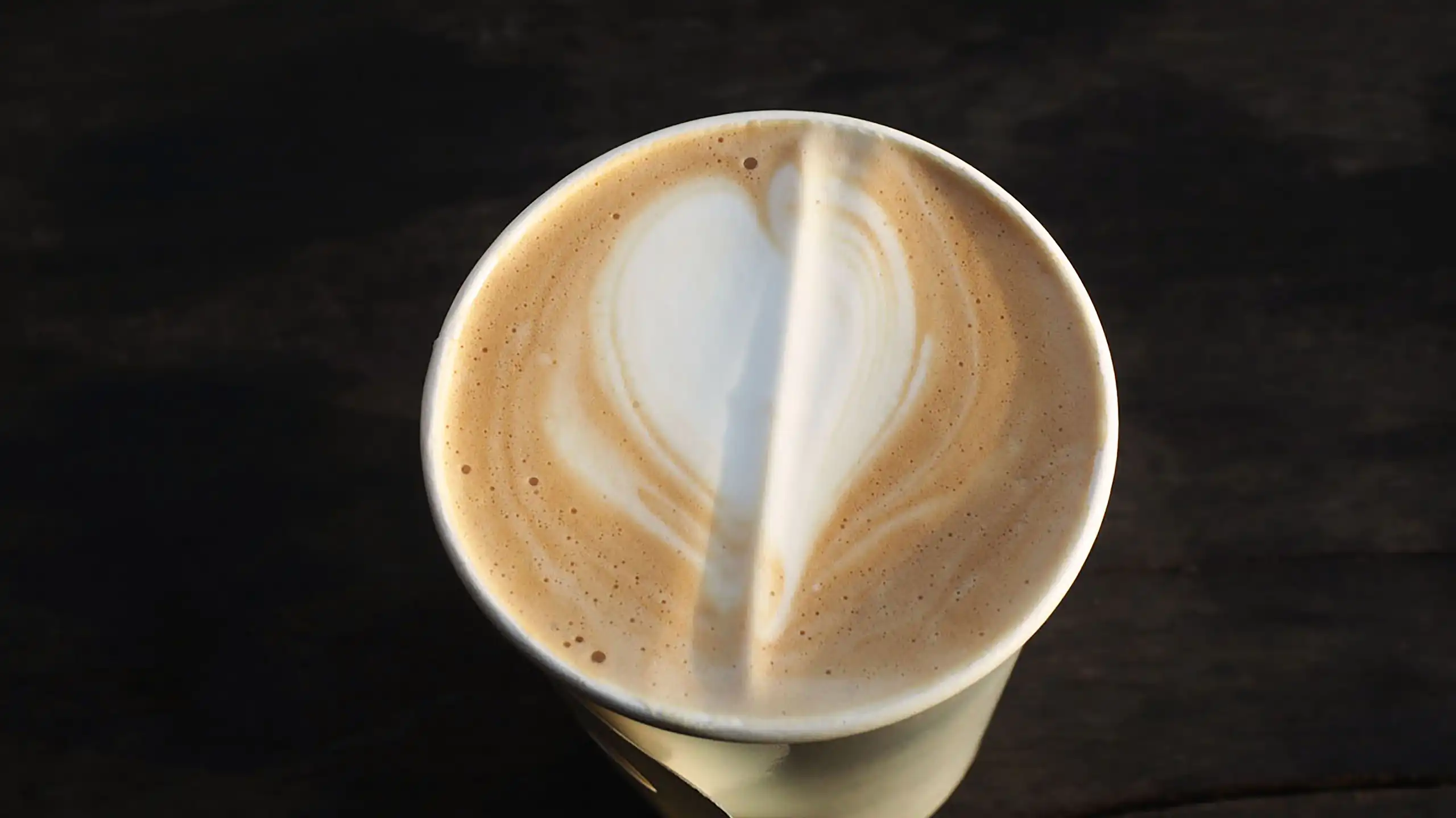 Un vaso de plástico lleno de café con leche visto desde arriba.
