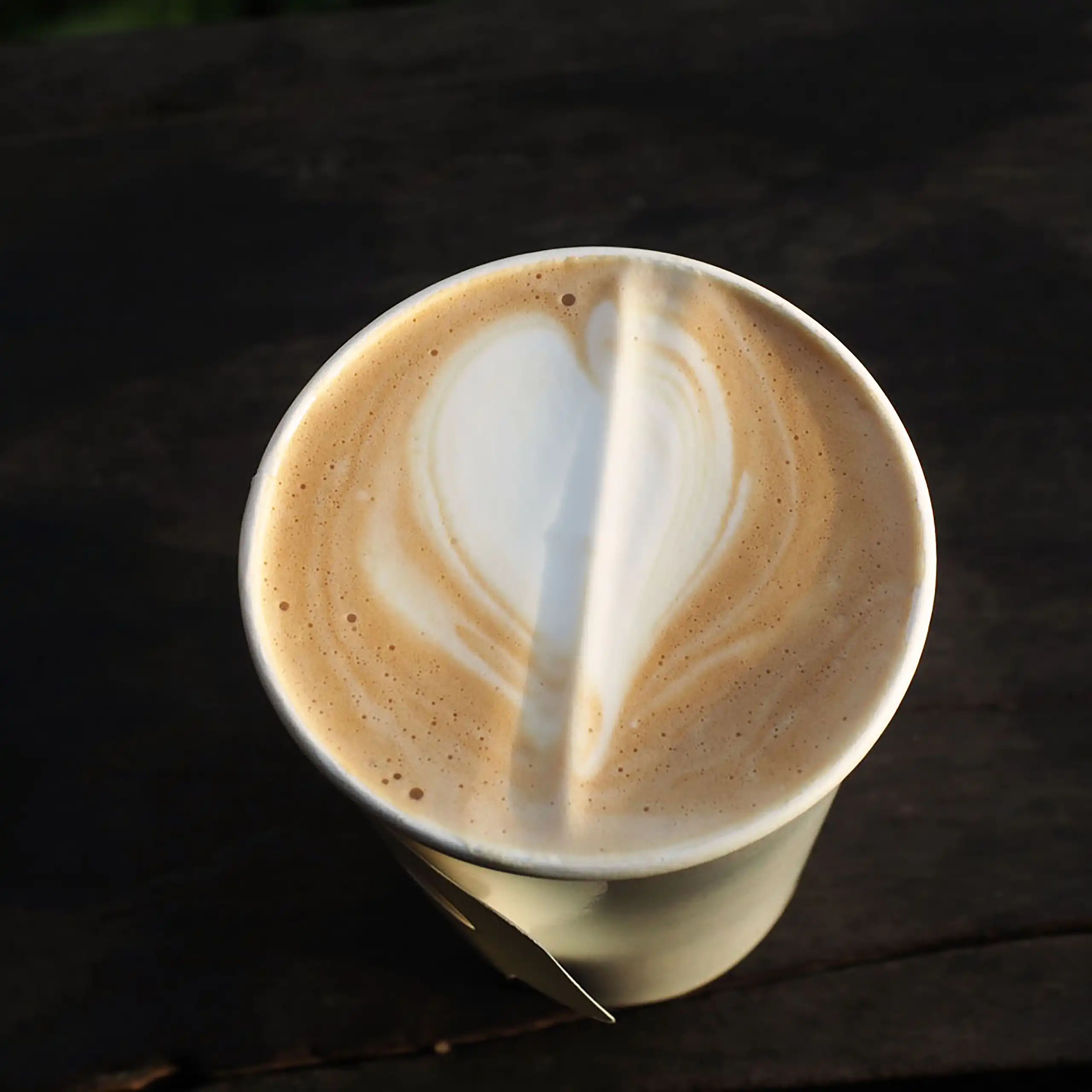 Un vaso de plástico lleno de café con leche visto desde arriba.