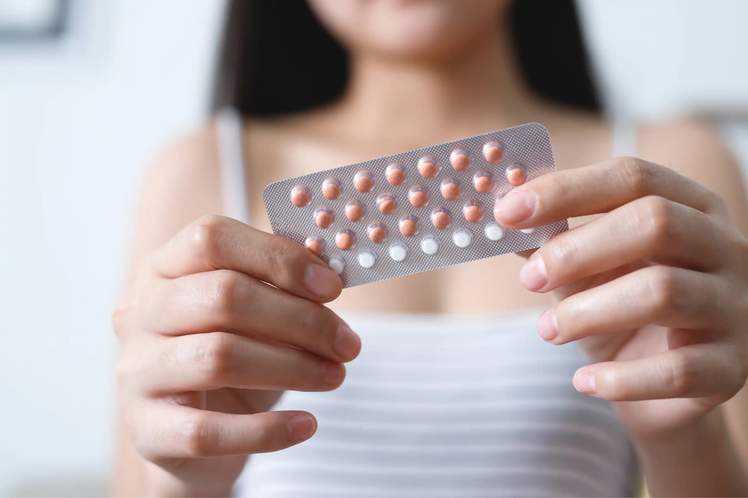 Une jeune femme tient dans ses mains une plaquette de pilules contraceptives.