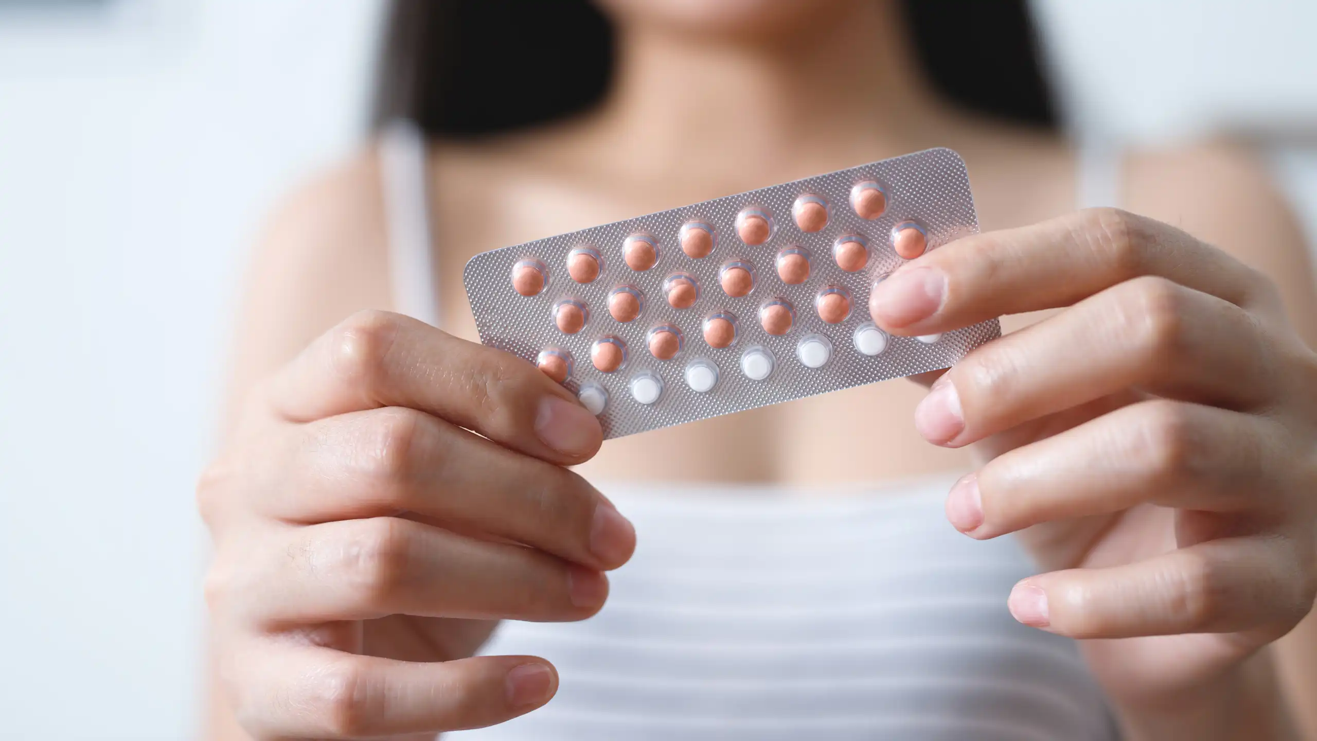 Une jeune femme tient dans ses mains une plaquette de pilules contraceptives.
