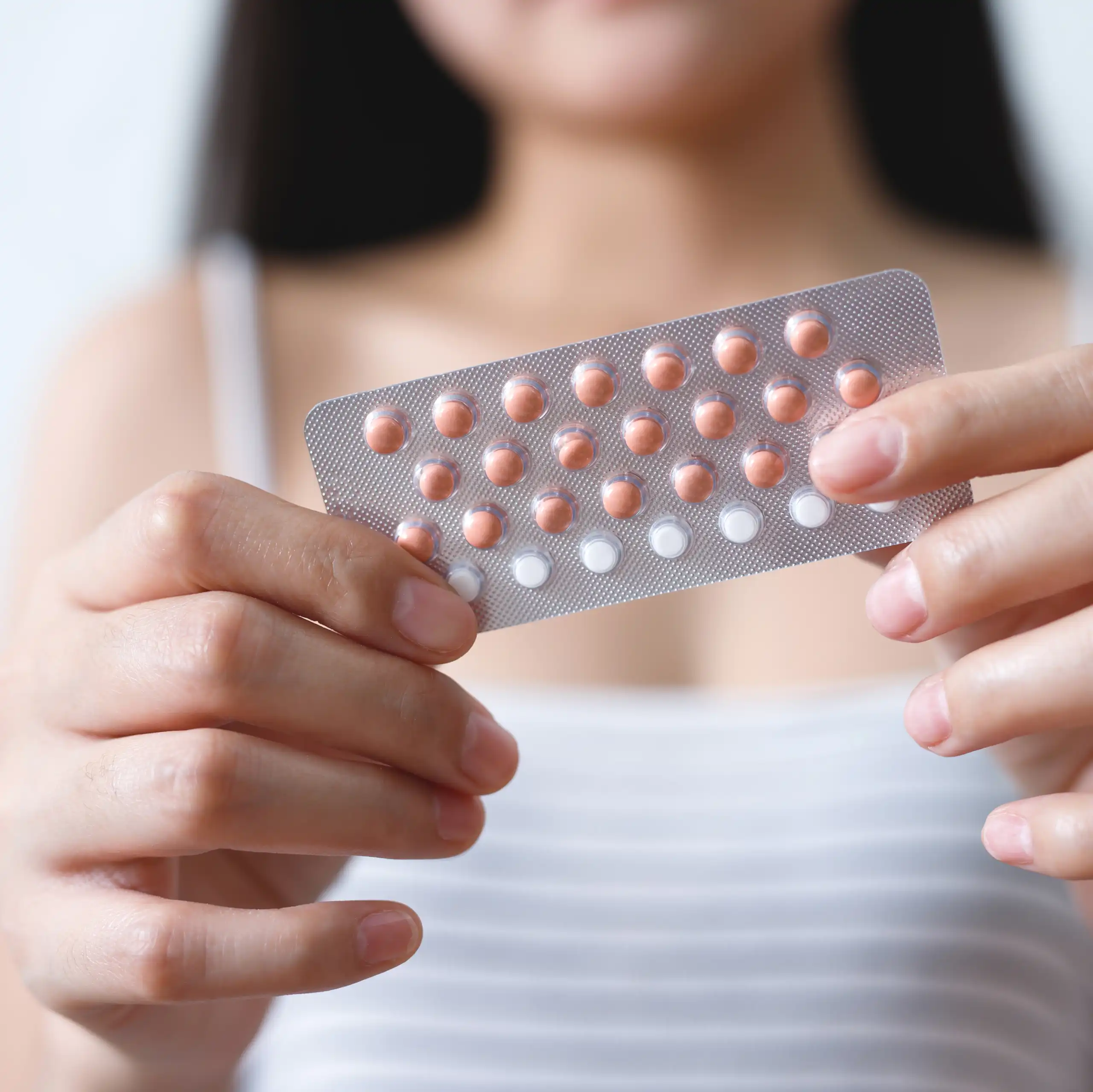 Une jeune femme tient dans ses mains une plaquette de pilules contraceptives.