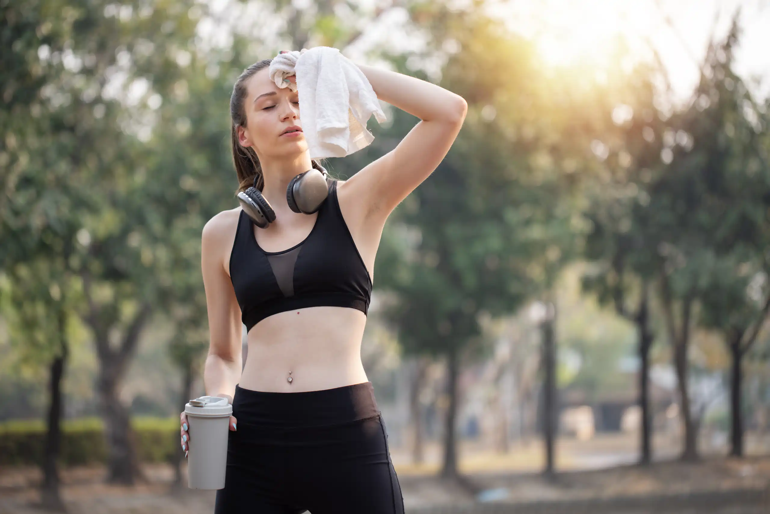 Une femme en tenue de sport s'éponge le front avec une serviette.