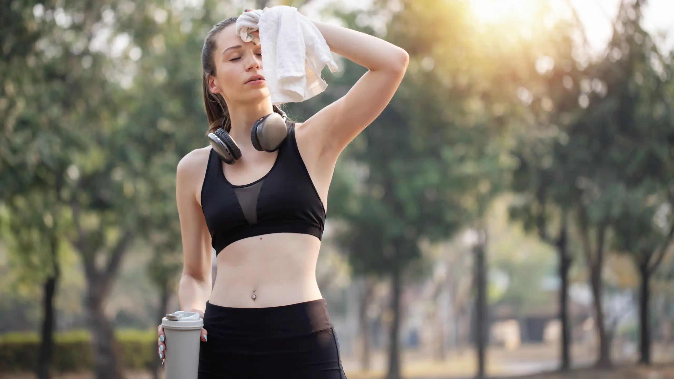 Une femme en tenue de sport s'éponge le front avec une serviette.