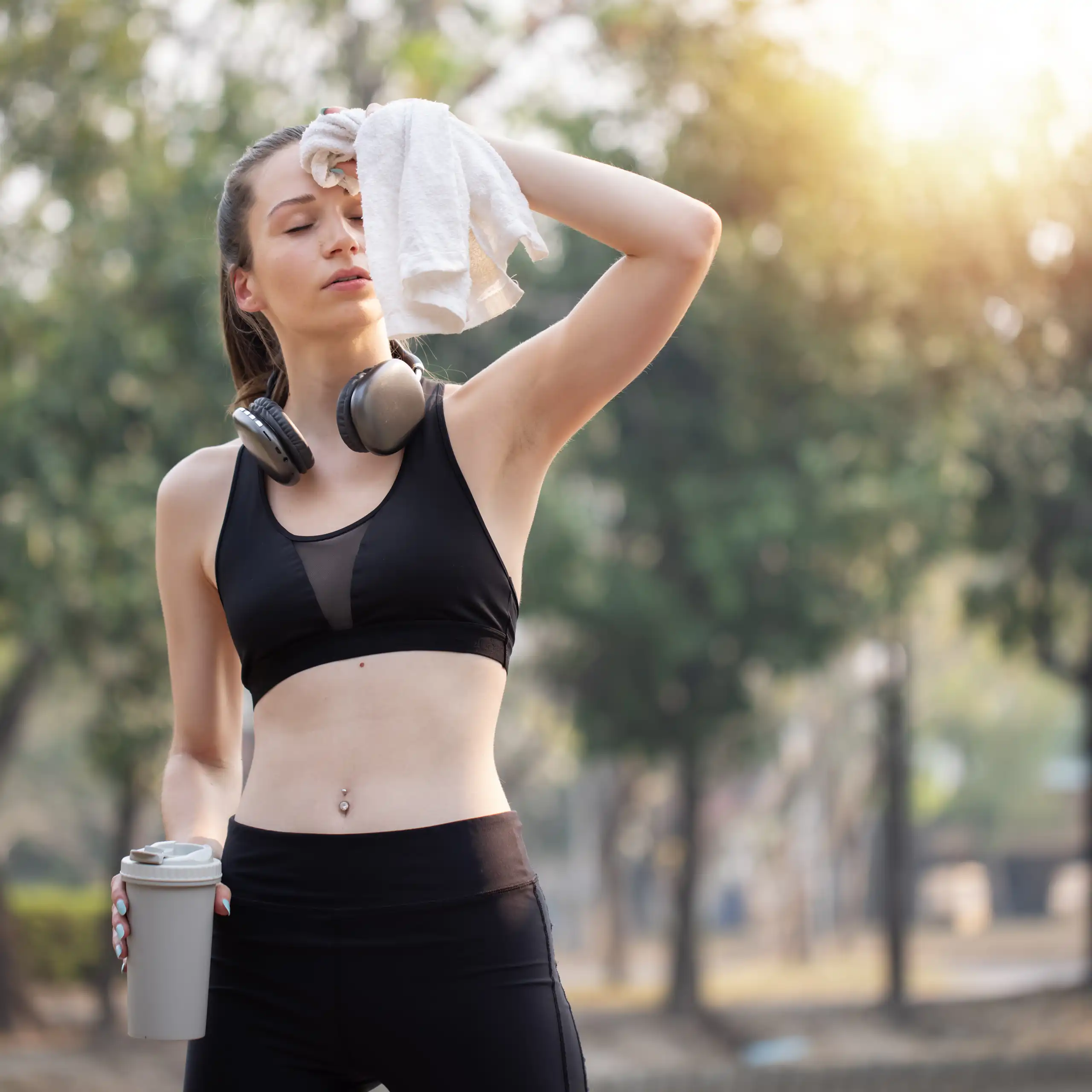 Une femme en tenue de sport s'éponge le front avec une serviette.