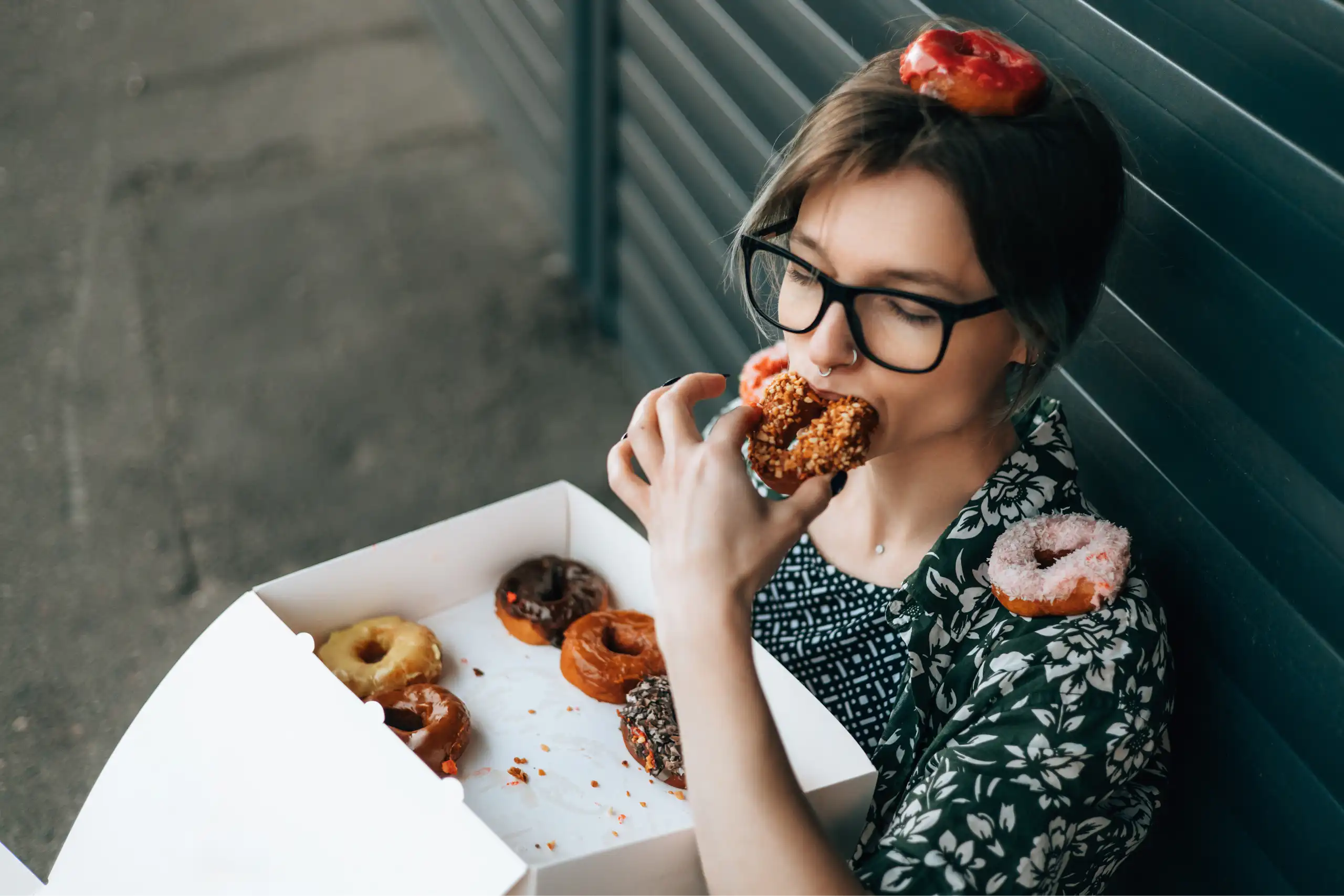 Une jeune femme mange une boite de donuts.